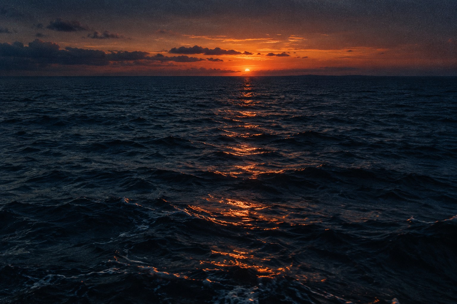 An orange sunset reflected across a deep blue ocean